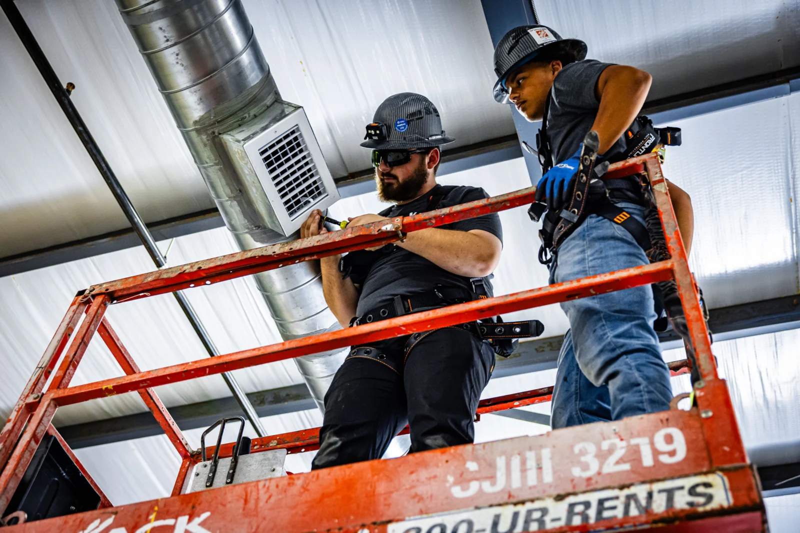 Two Kalos technicians working on commercial ductwork from a scissor lift