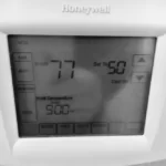 Close view of a wall-mounted Honeywell thermostat with its display active.