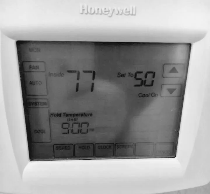 Close view of a wall-mounted Honeywell thermostat with its display active.
